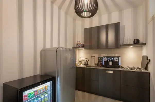 Moderne kitchenette aan de Van Baerlestraat met koelkast vol frisdrank, koffiezetapparaat en gasfornuis.